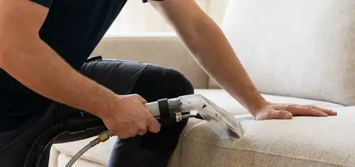Professional upholstery cleaner deep-cleaning a fabric sofa with a handheld extraction tool, Cambridge, MA.